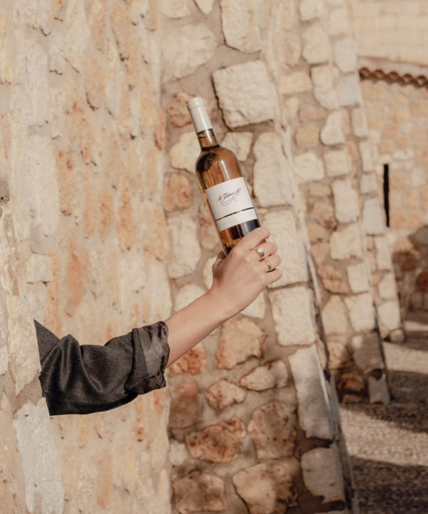 jane holding a bottle of rose behind a wall