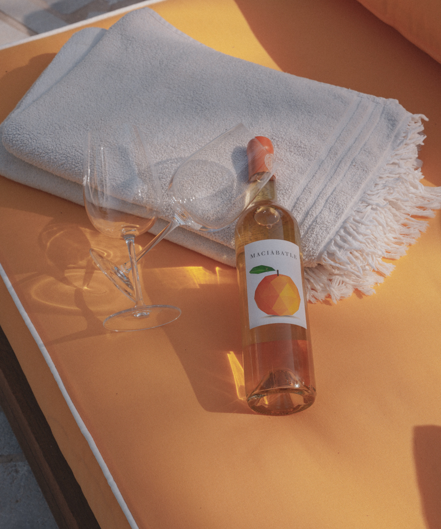 Orange wine with empty wineglasses on sunbed