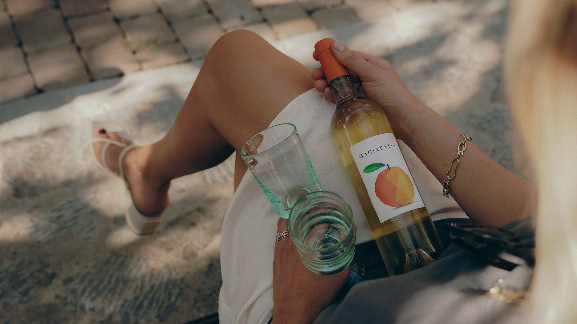 Orange wine with glasses on Jane's leg